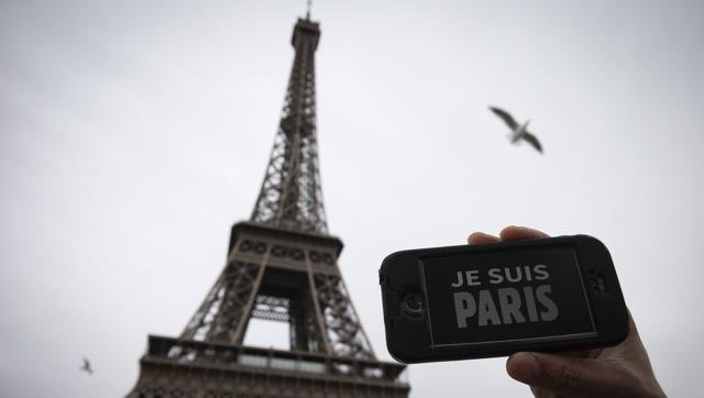 Una persona sujeta un móvil con el mensaje "Je suis Paris" frente a la Torre Eiffel