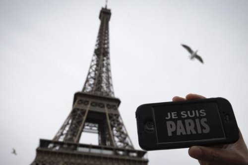 Una persona sujeta un móvil con el mensaje "Je suis Paris" frente a la Torre Eiffel
